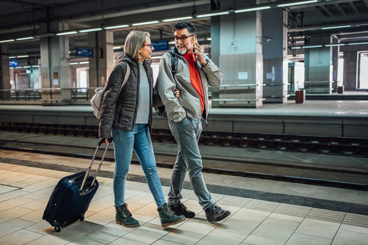 Couple walking at a train station in Europe, man on phone