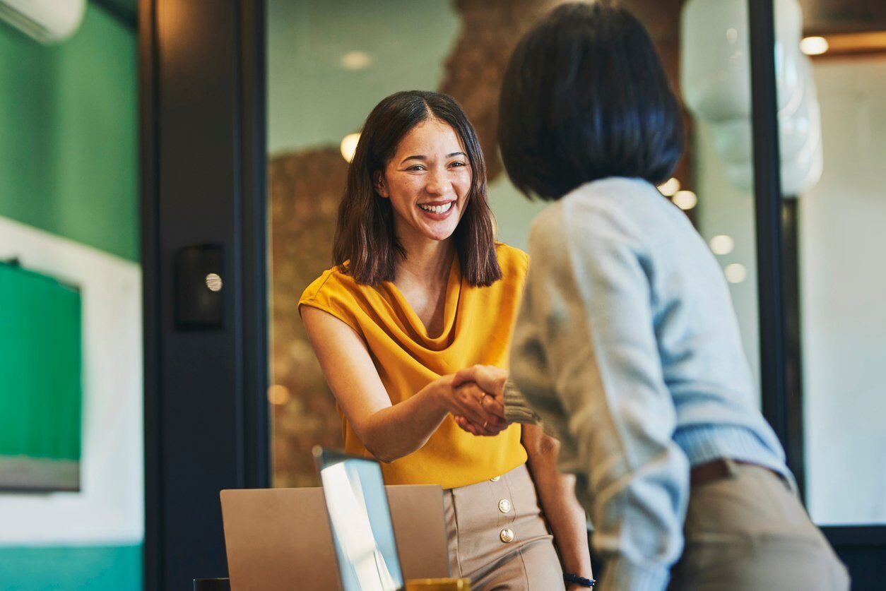 Woman greeting each other infront of a boardroom.